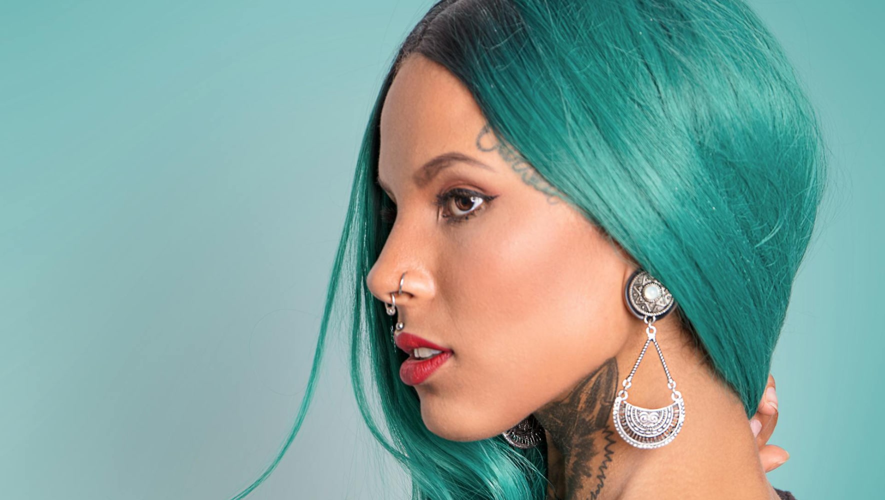A stunning woman with vibrant green hair and stylish piercings, showcasing her beauty after a visit to Sofoklis Hair Salon.